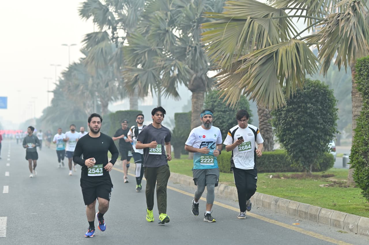 A misty morning road race under palm trees, a pack of runners mid-stride.