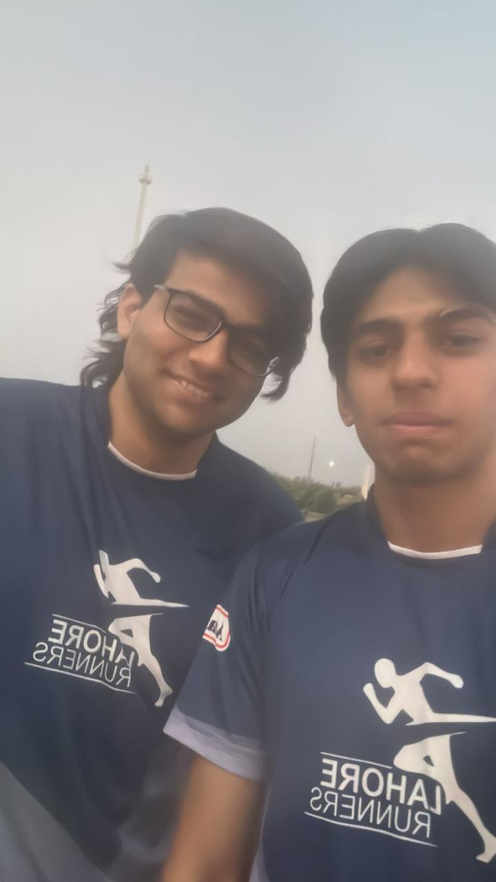 Selfie of the two of us in navy Lahore Runners shirts under a pale sky.