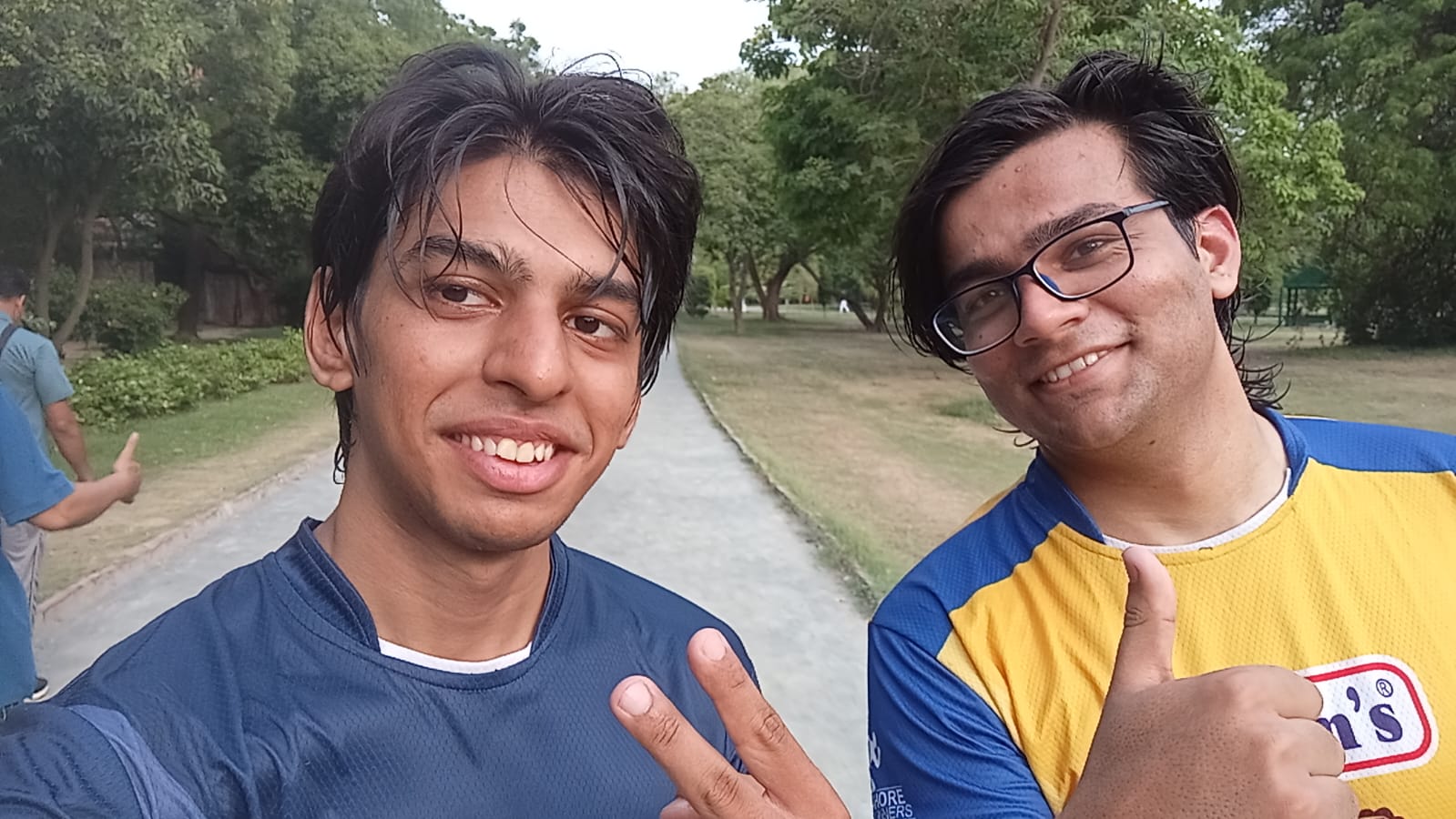 Sweaty post-run selfie in a green park, a peace sign and a thumbs up.