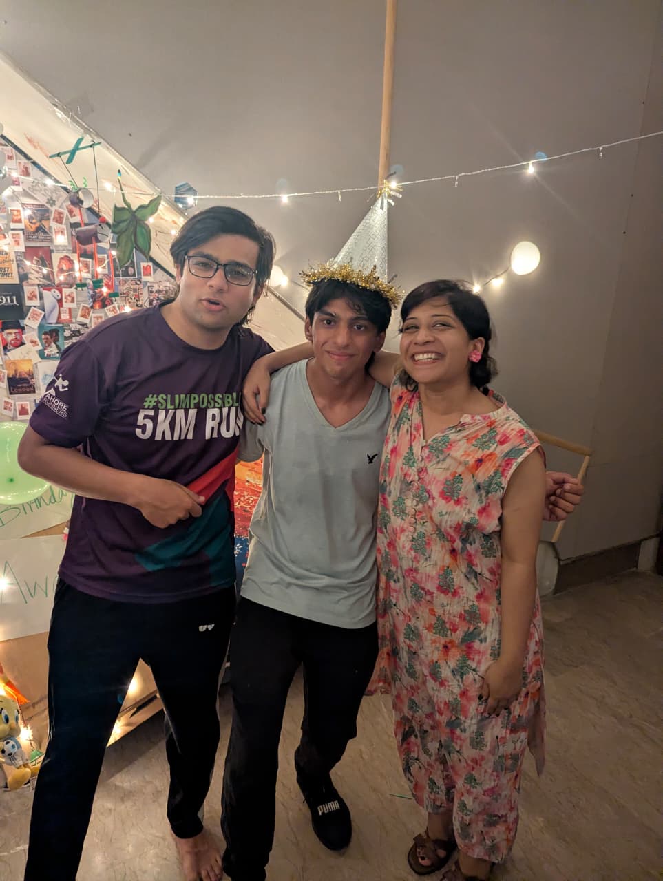 Three of us together under fairy lights, party hat on.